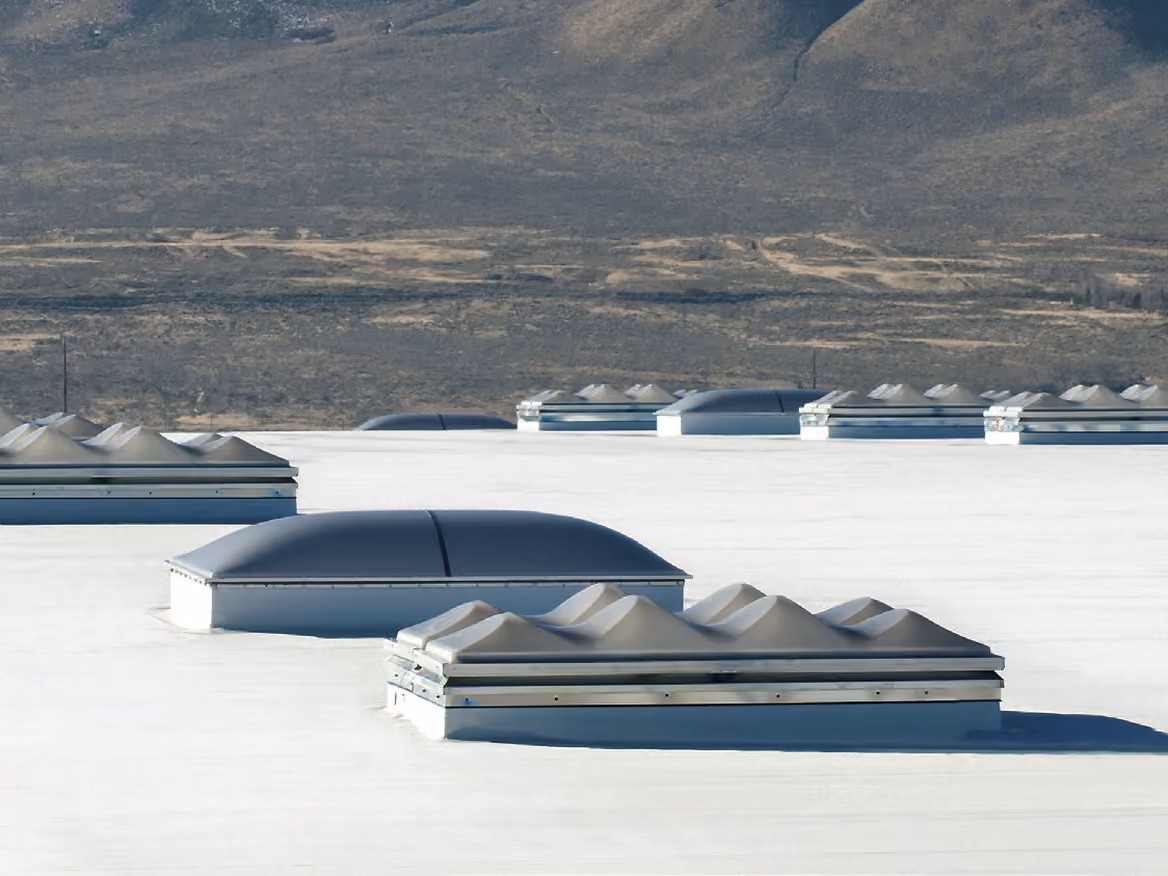 A domed skylight and a ridged skylight on raised frames on a white flat roof, more skylights and mountains behind them