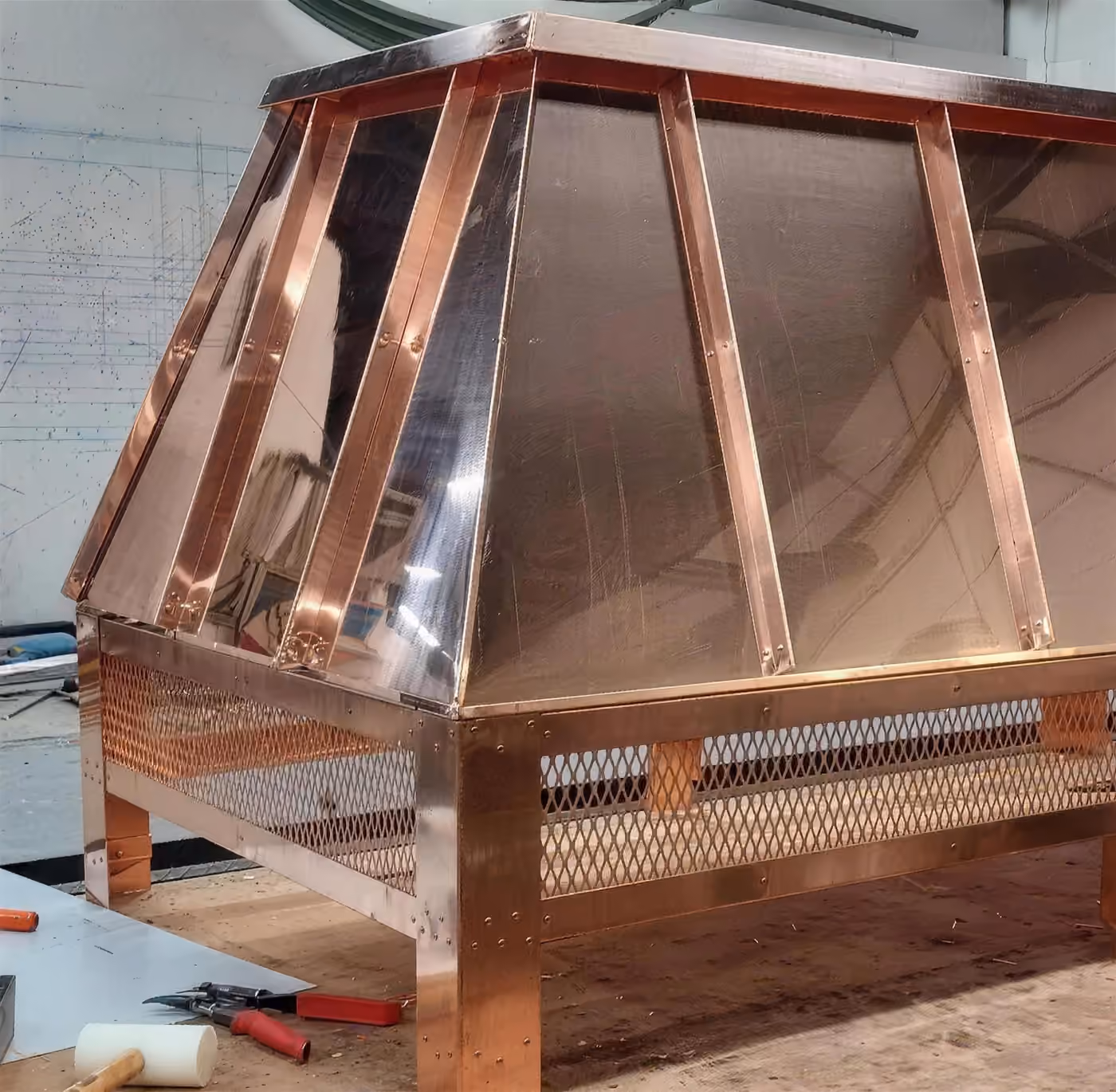 A copper cupola with a hipped standing seam roof over a mesh louver base, fabricated in the shop before it goes up on the roof